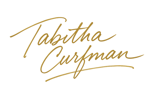 "Tabitha Curfman" on one line written as a dramatic, fast handwritten signature with a ball point pen in gold ink 